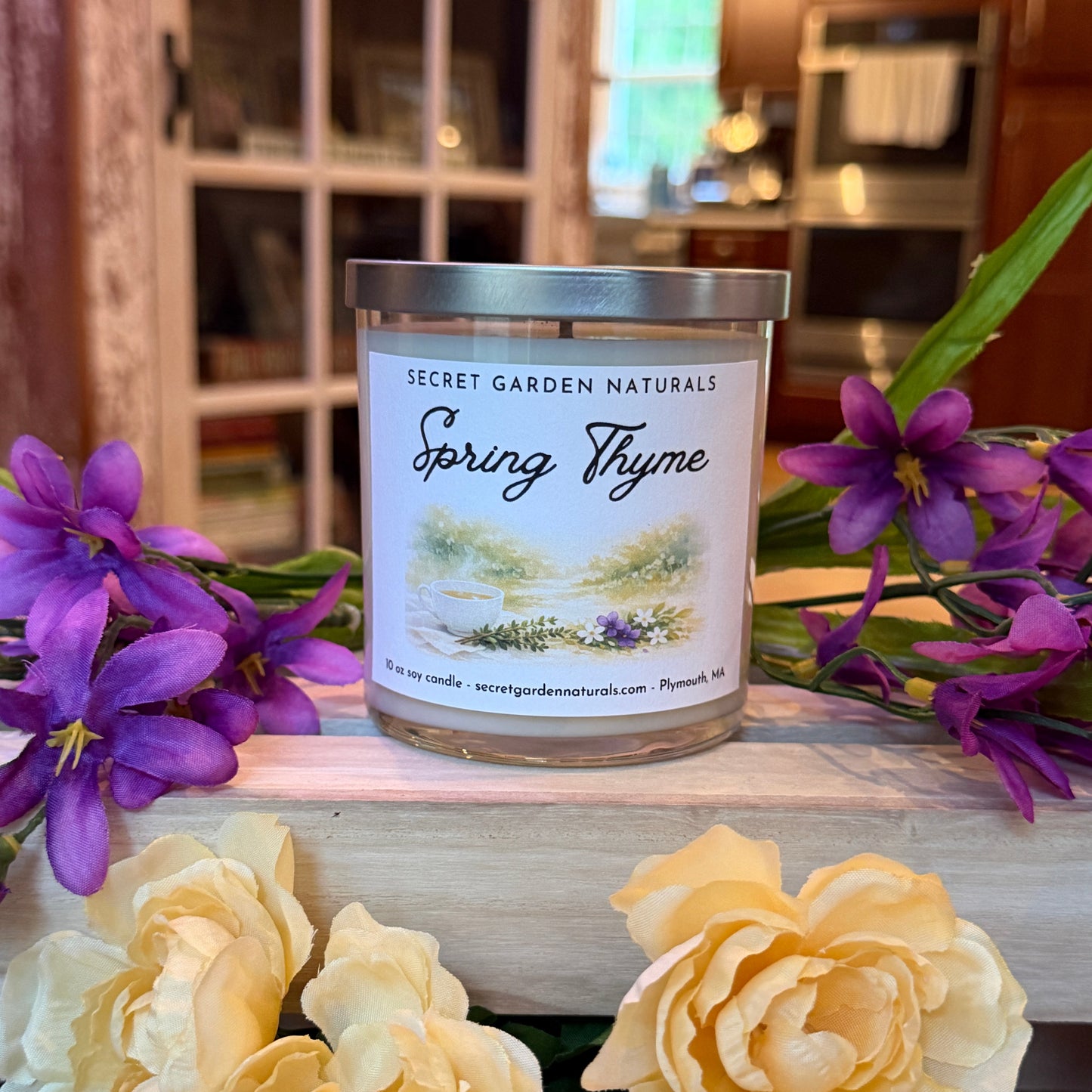 Spring Thyme candle on a wooden surface with purple and yellow flowers.