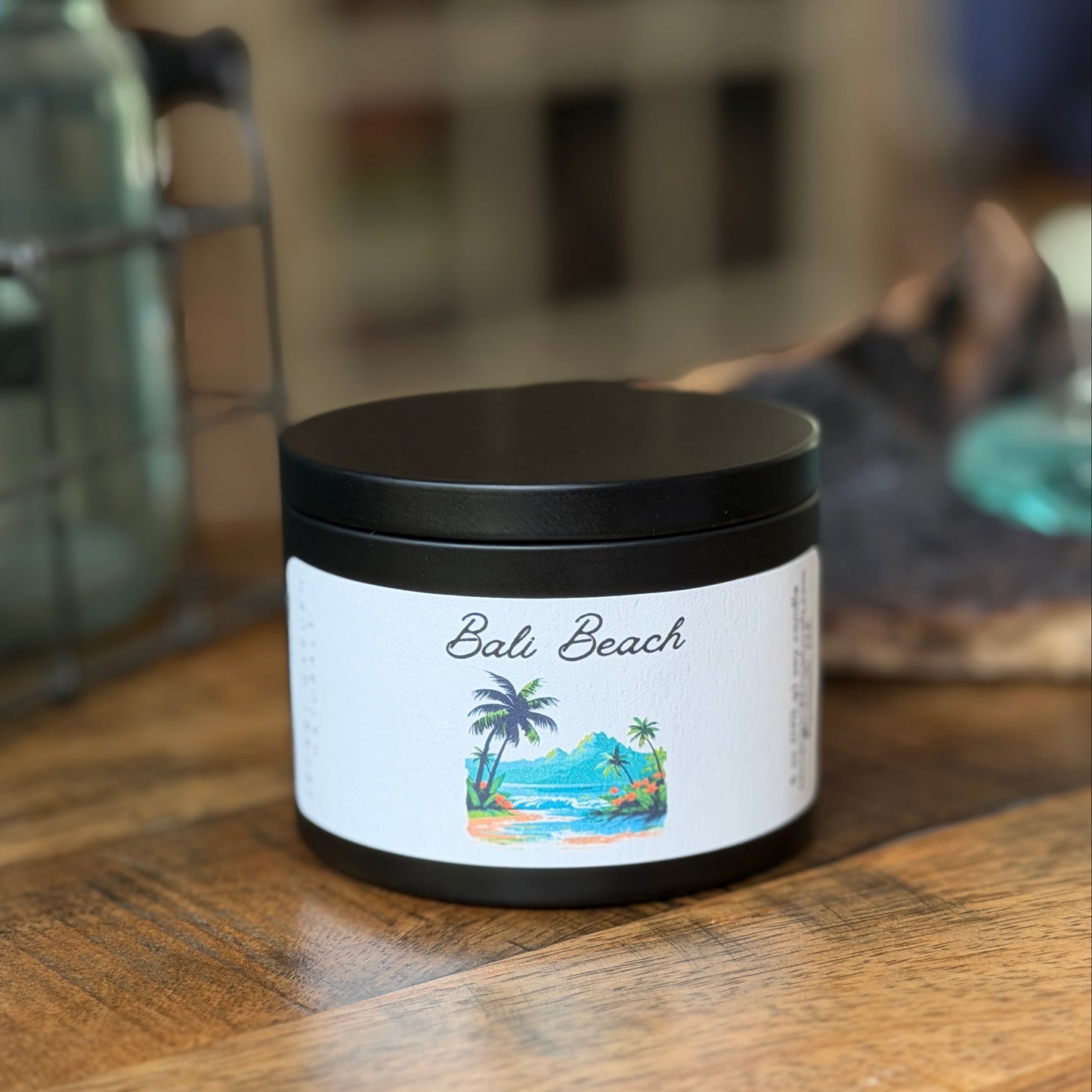 Candle tin labeled 'Bali Beach' on a wooden surface with a blurred background