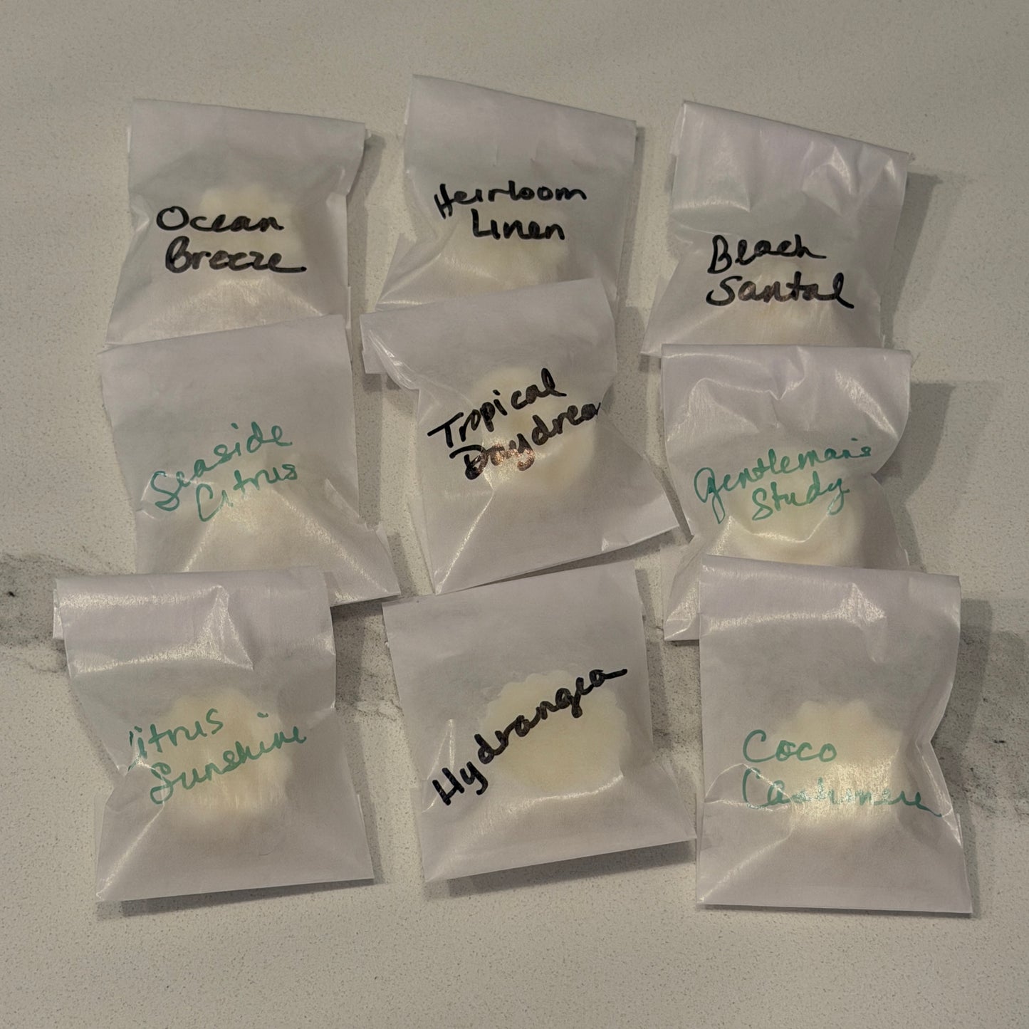Assorted scented wax melts in clear packaging with labels on a gray surface