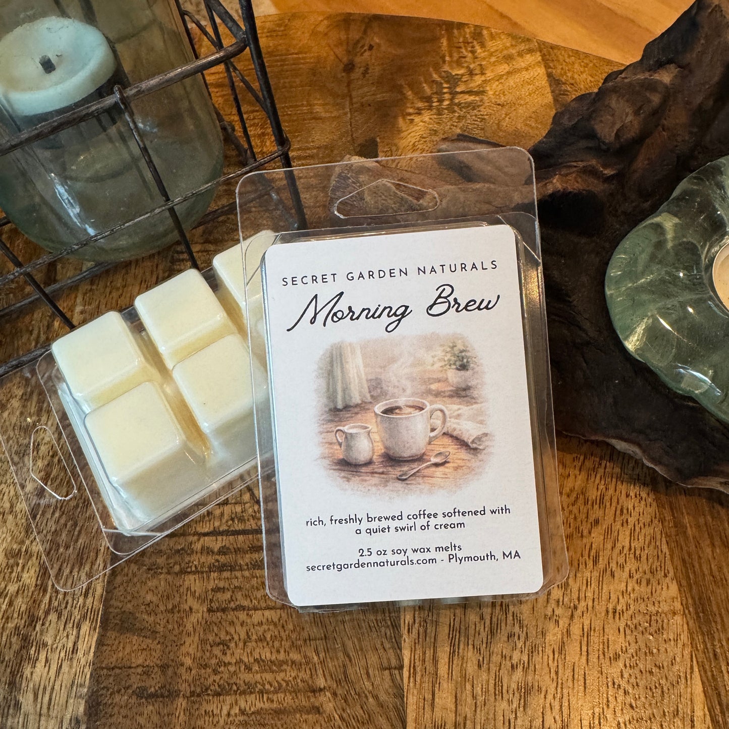 Packaged Moring Brew wax melts on a wooden surface with a candle in the background