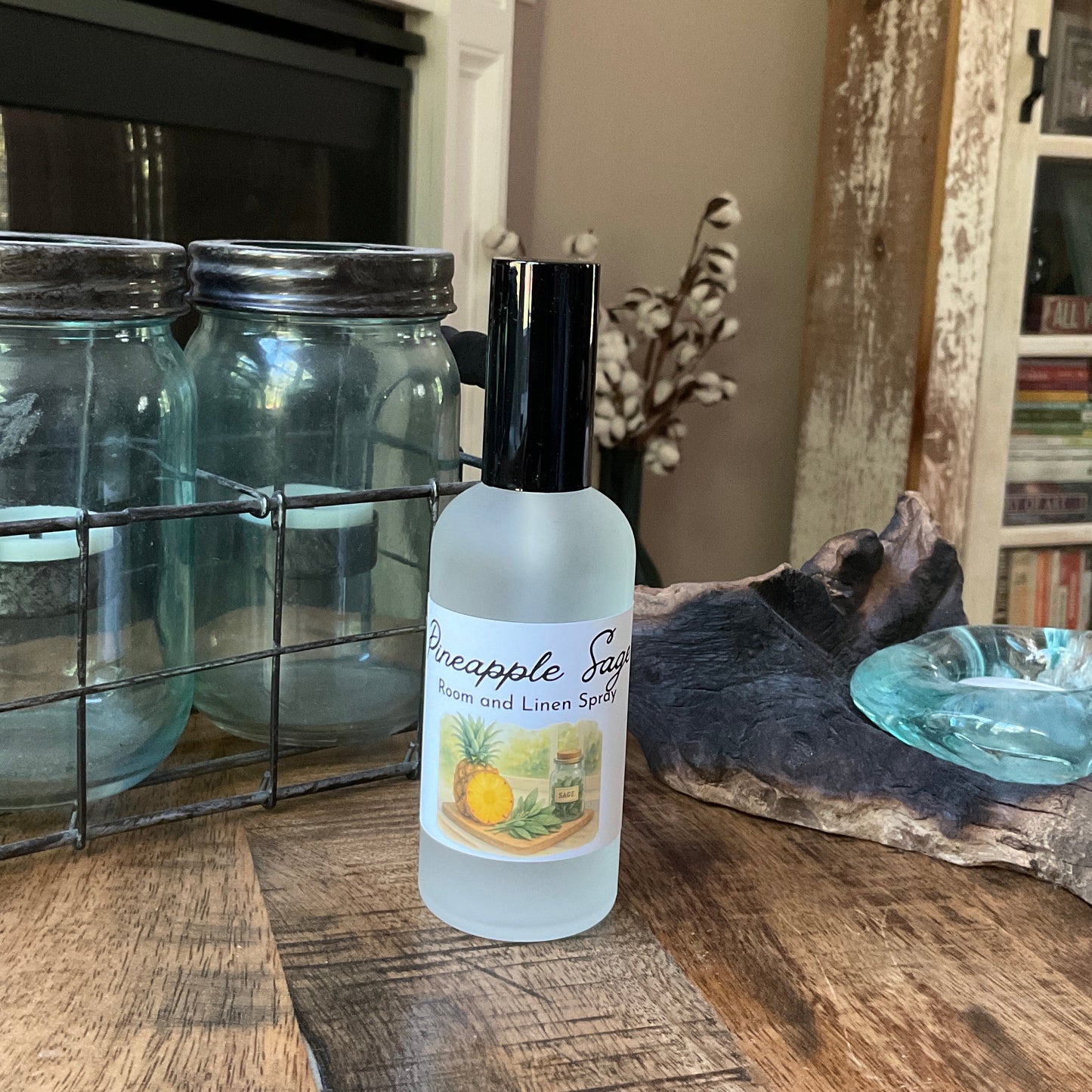 Bottle of Pineapple Sage essential oil on a wooden surface with decorative items in the background.