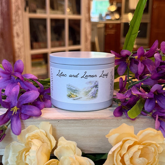 Lilac and Lemon Leaf candle tin  with a label surrounded by purple and yellow flowers in a kitchen setting