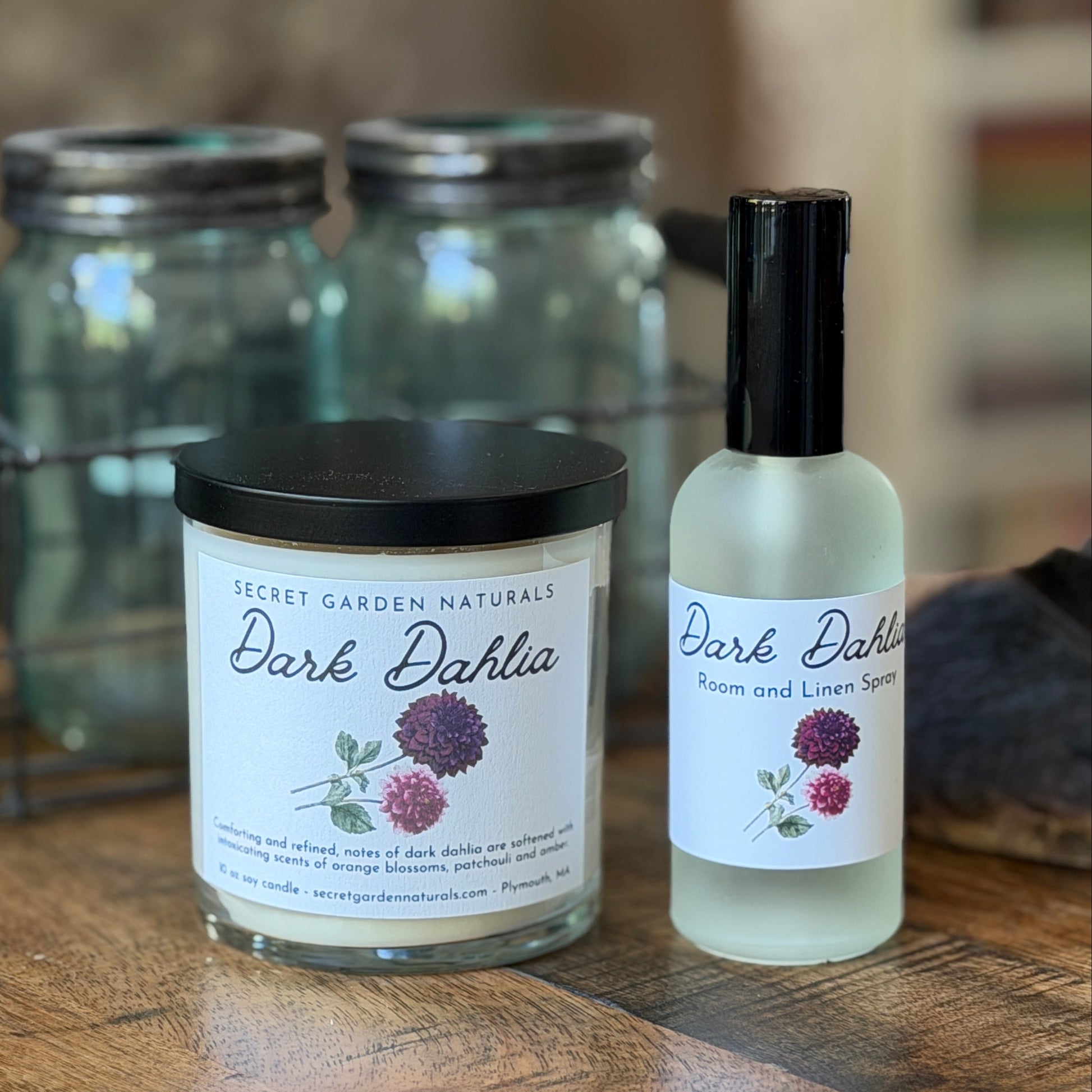 Dark Dahlia candle and room spray on a wooden surface with jars in the background