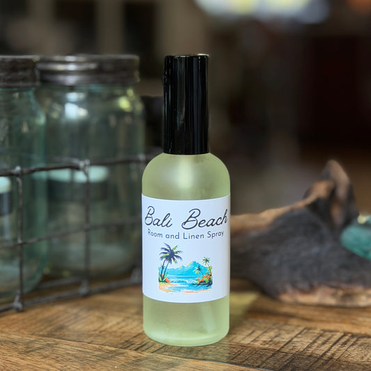 Spray bottle of Bali Beach Room and Linen spray on a wooden table with jars in the background.