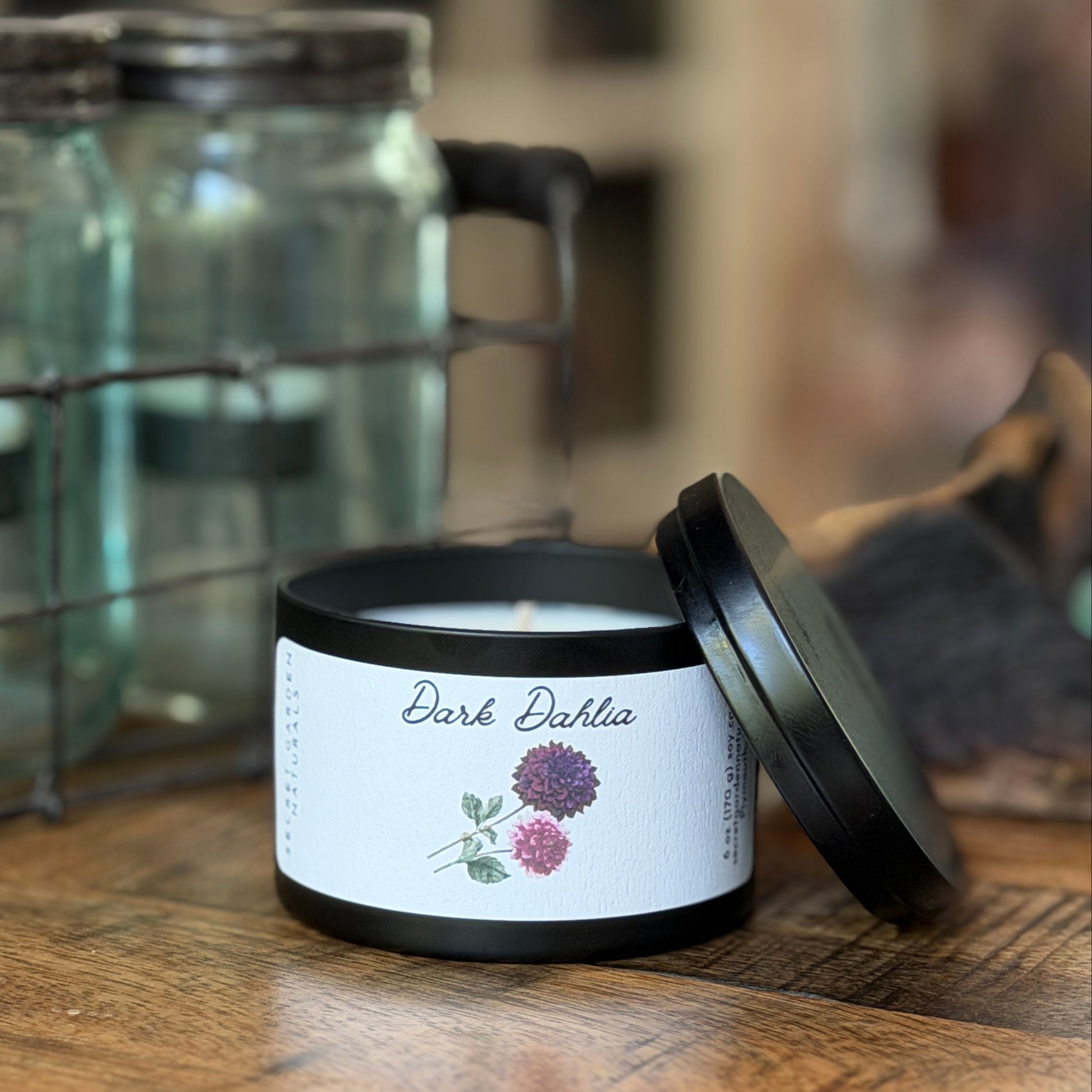 Black candle tin with 'Dark Dahlia' label on a wooden surface