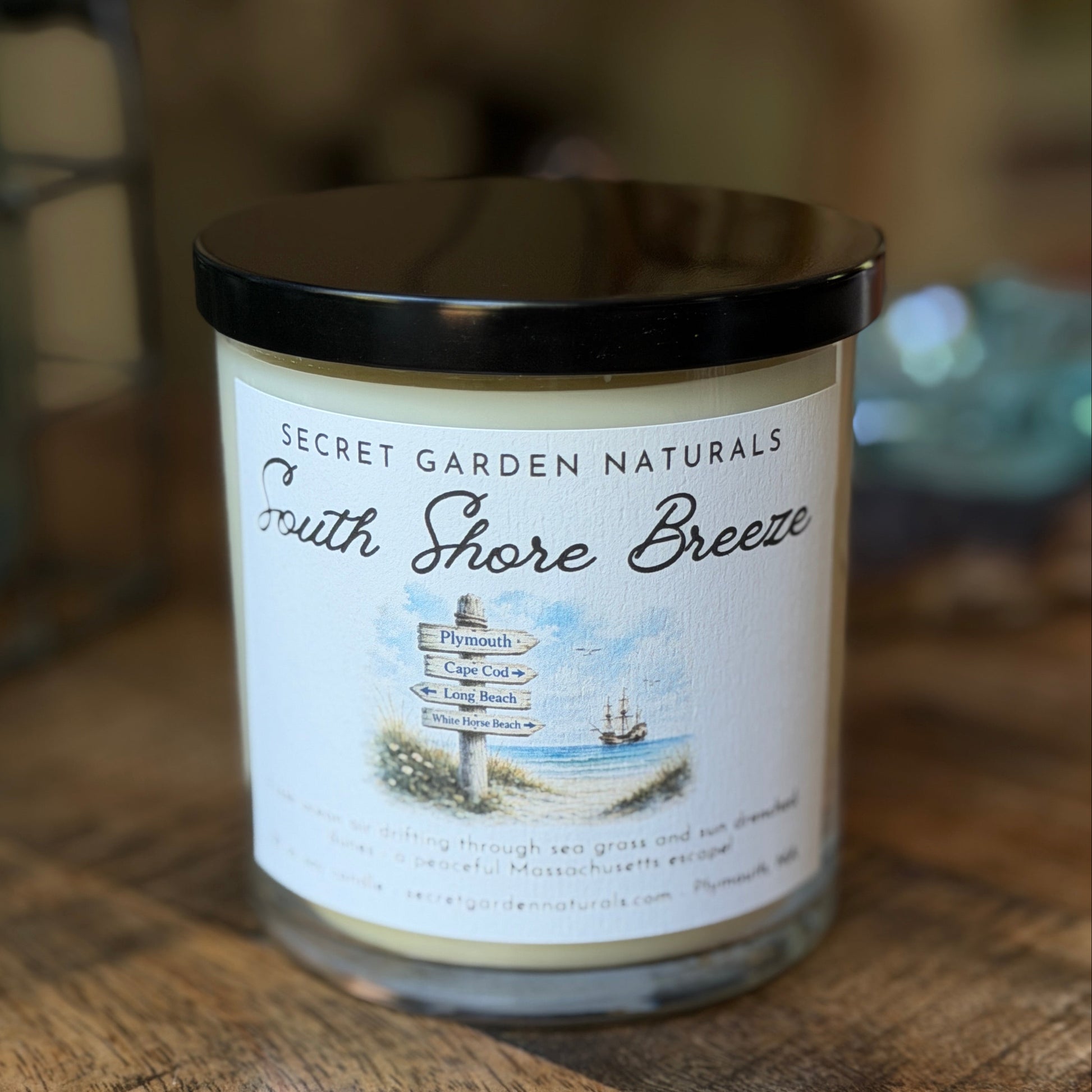 Candle labeled 'Smith Shore Breeze' from Secret Garden Naturals on a wooden surface.