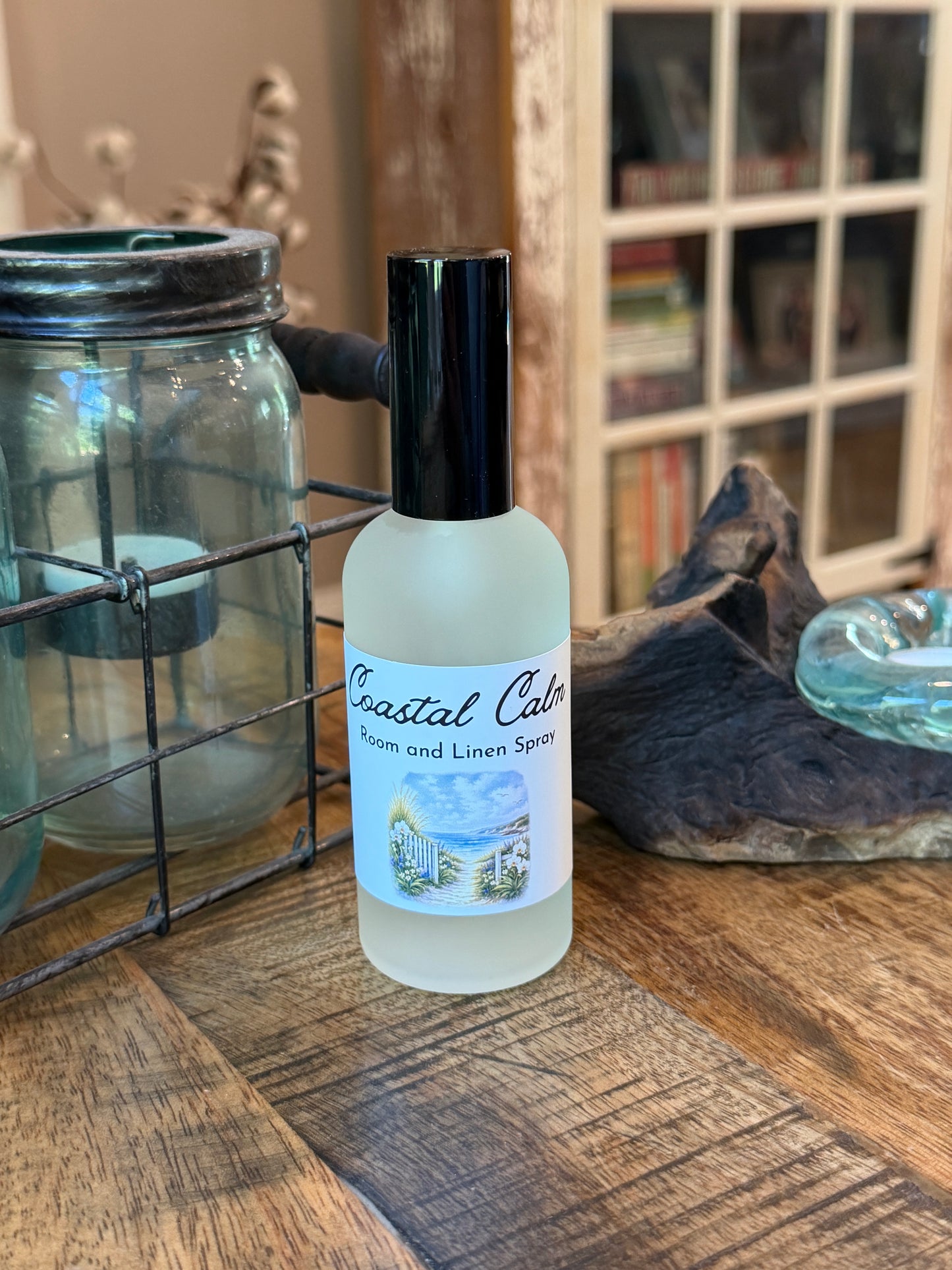 Coastal Calm room / linen spray on a wooden table with a bookcase in the background