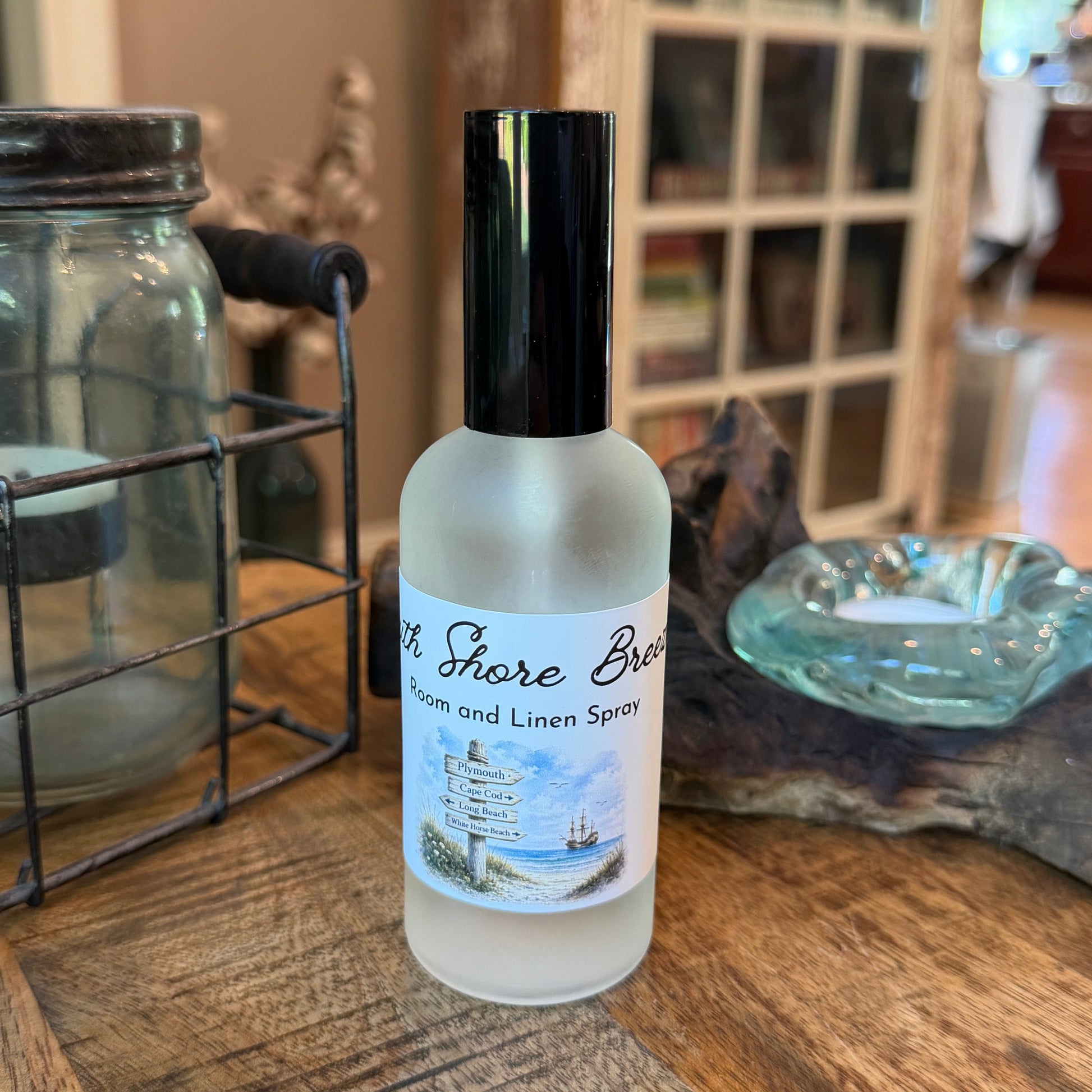 Bottle of South Shore Breeze room and  linen spray on a wooden surface with a blurred background