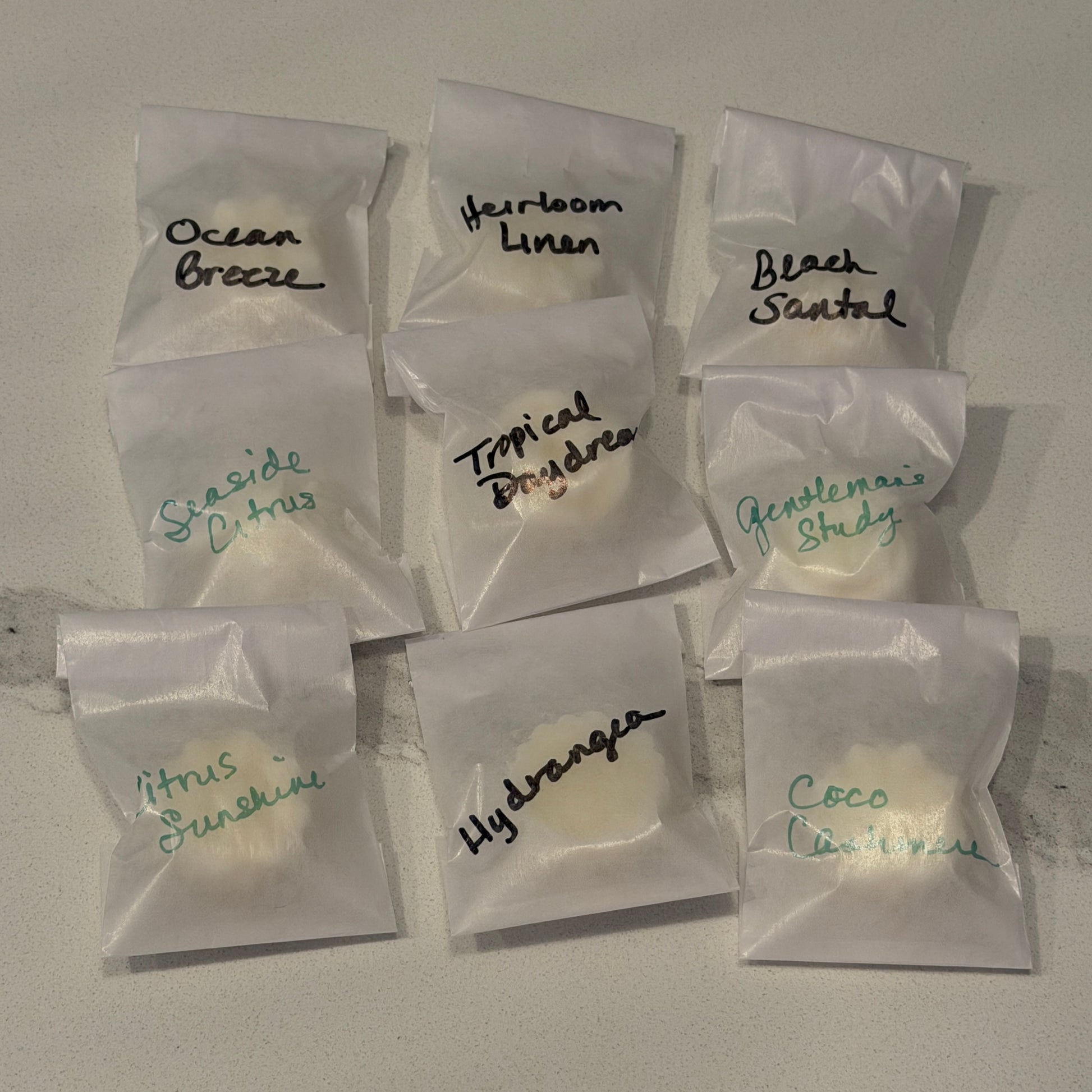 Assorted scented wax melts in clear packaging with labels on a gray surface