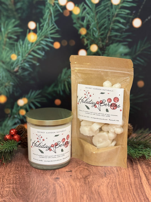 Candle and bag of 'Holiday Berries' product with Christmas tree and lights in the background