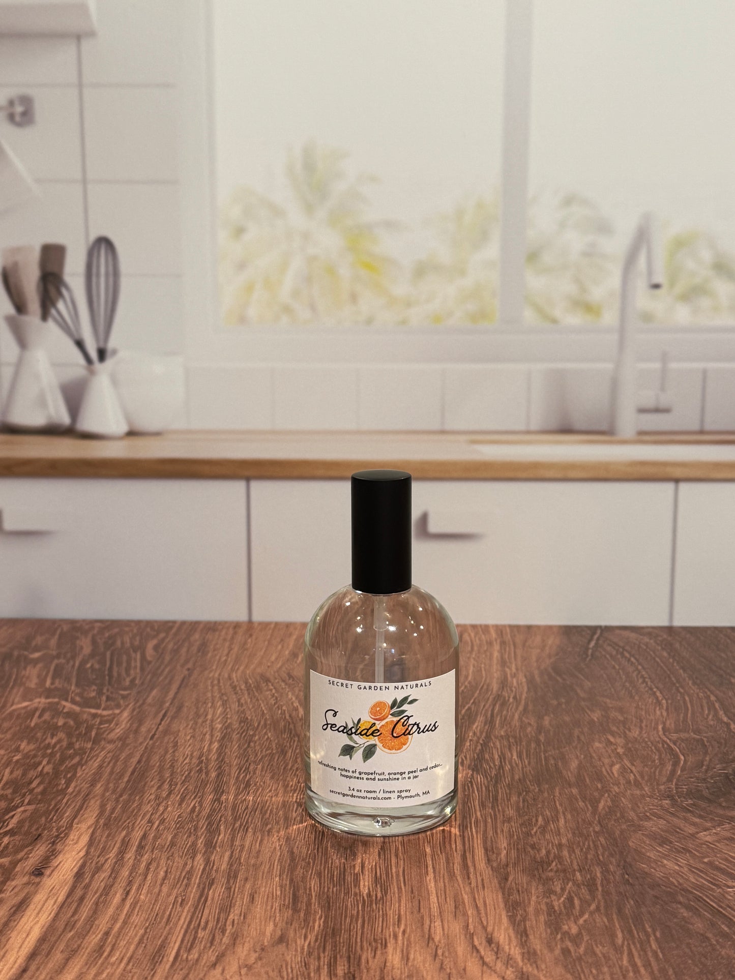 Bottle of Seaside Citrus room/linen spray on a wooden surface with a blurred kitchen background