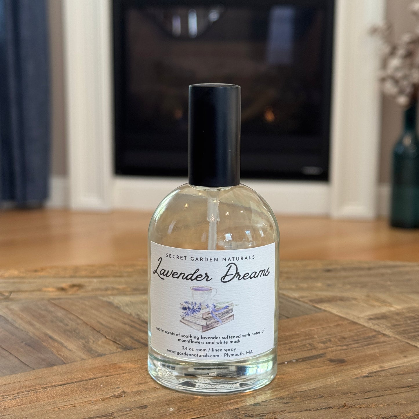 Bottle of Lavender Dreams room / linen spray on a wooden table with fireplace in the background