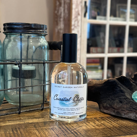 Bottle of 'Coastal Cliffs' room / linen spray with a label on a wooden surface