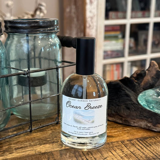 Bottle of 'Ocean Breeze' room / linen spray on a wooden surface with a blurred background