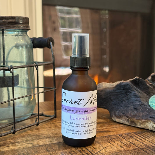 Bottle of 'Secret Mist' lavender toilet spray on a wooden surface.
