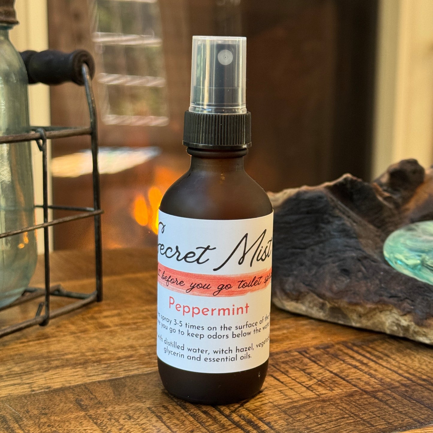 Bottle of 'Secret Mix' peppermint toilet spray on a wooden surface with a blurred background