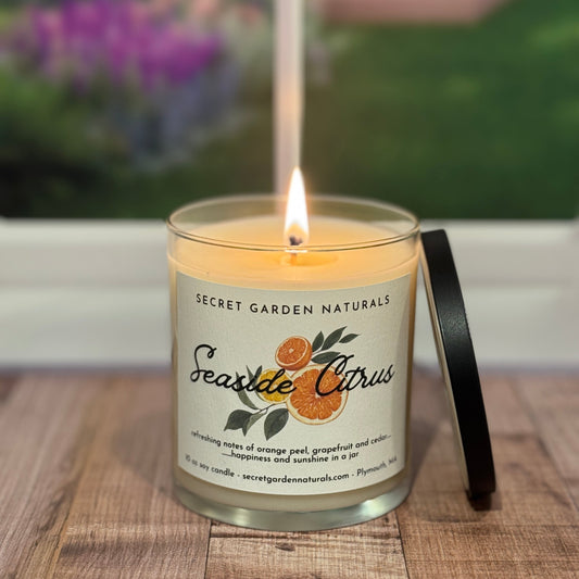 Lit candle with 'Secret Garden Naturals' label on a wooden surface